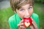 Boy eating an apple with a heart shape